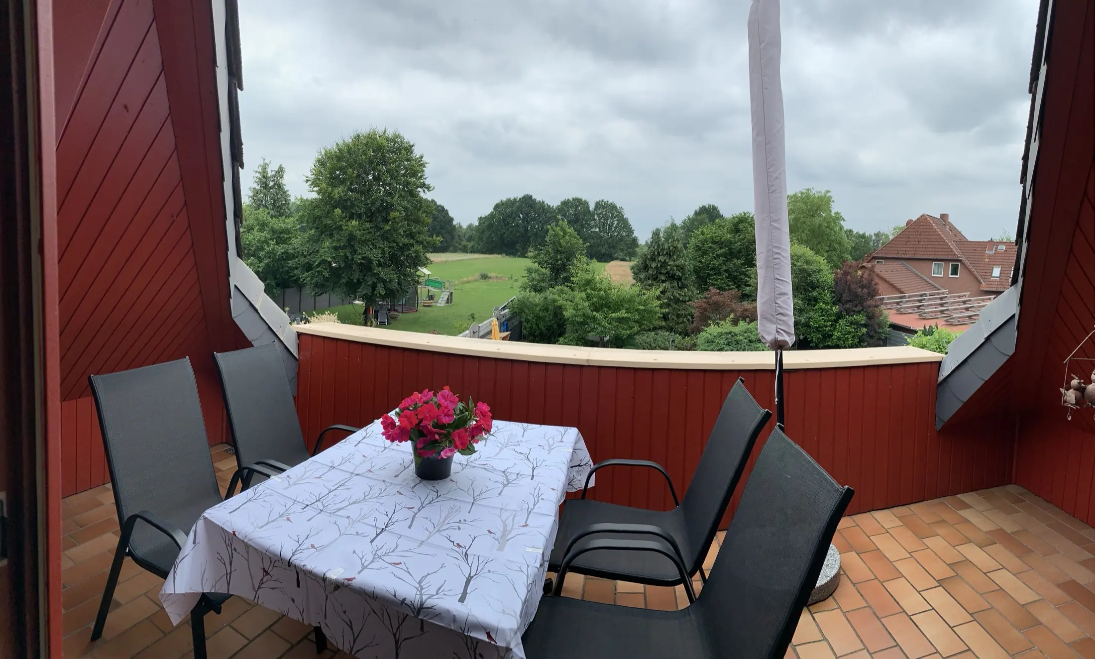Südbalkon mit Tisch, vier Stühlen und Sonnenschirm